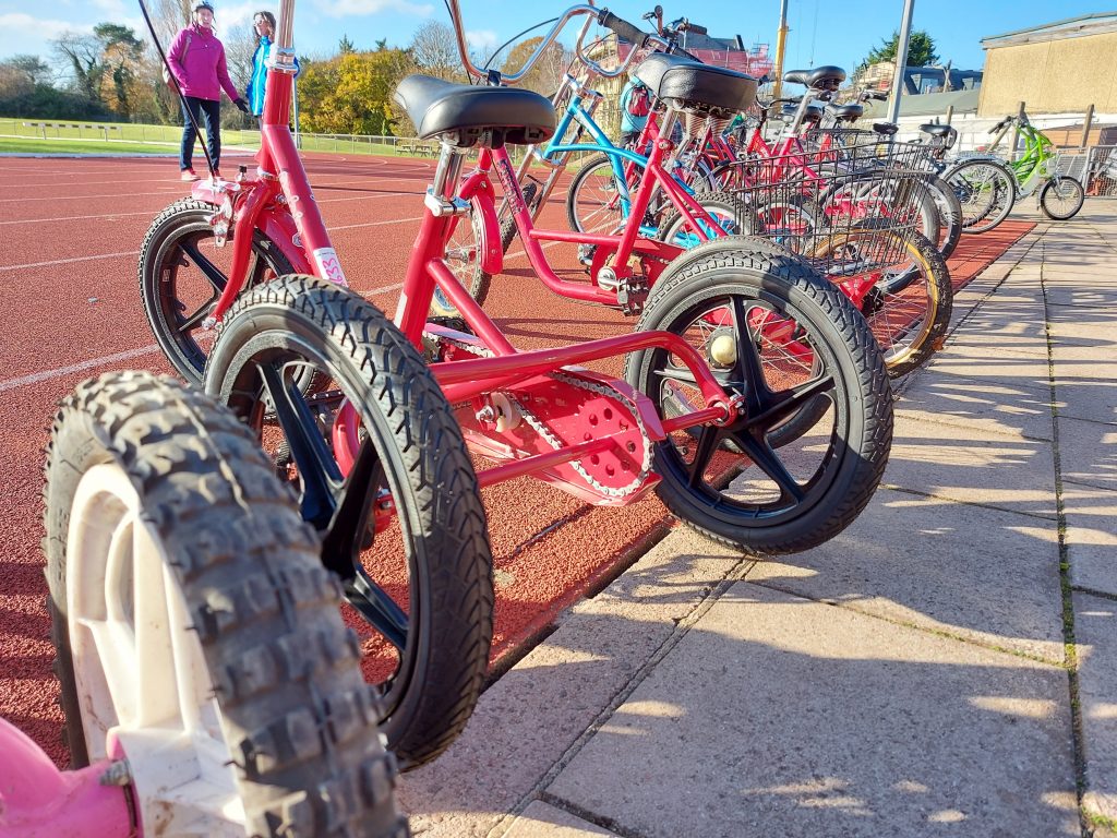 Several tricycled lined up at an event for disability cycling in Kingston