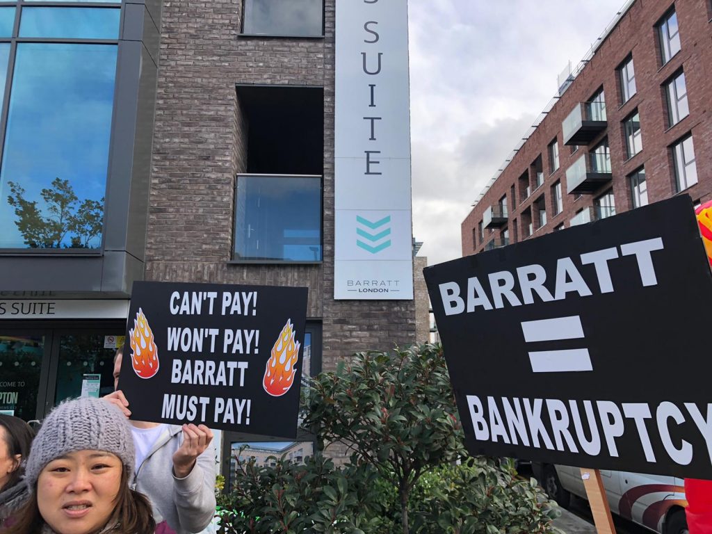 Protesters outside the Barratt London marketing suite, in Upton Park. They hold signs saying Barratt = Bankruptcy, and Can't pay, won't pay, Barratt must pay!