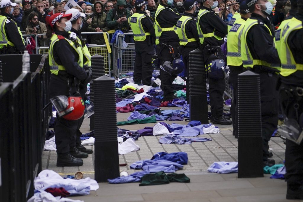 Police officers stand outside Downing Street as NHS uniforms lie on the ground, during a VCOD protest, in London, Saturday, Jan. 22, 2022.(AP Photo/Alberto Pezzali)