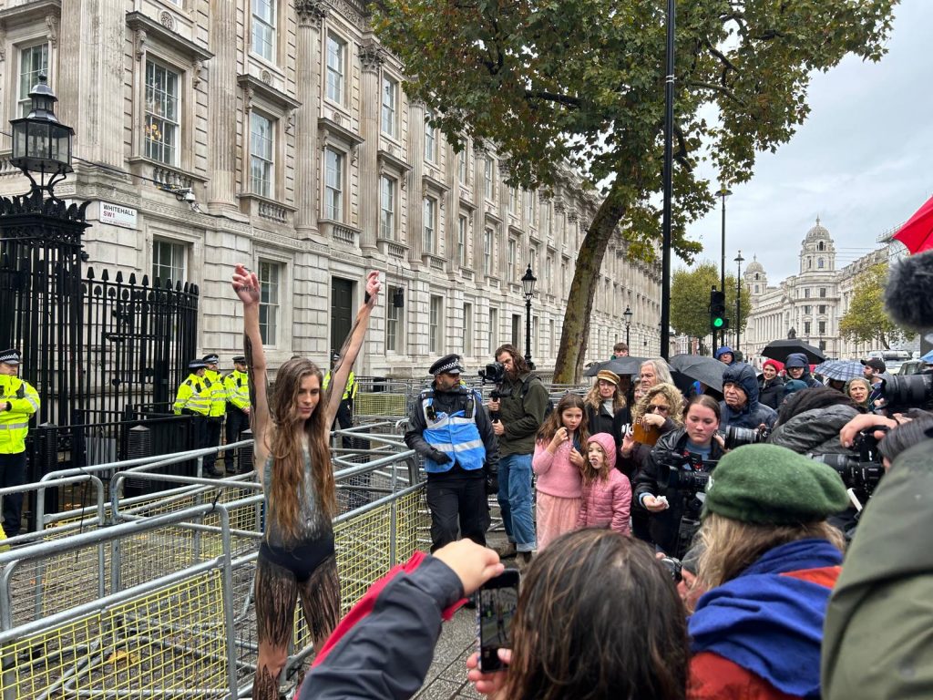 Hannah Bourne-Taylor raising her arms addressing crowds outside Downing Street