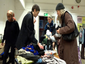 Two women exchange clothes in a clothing swap in Hackney